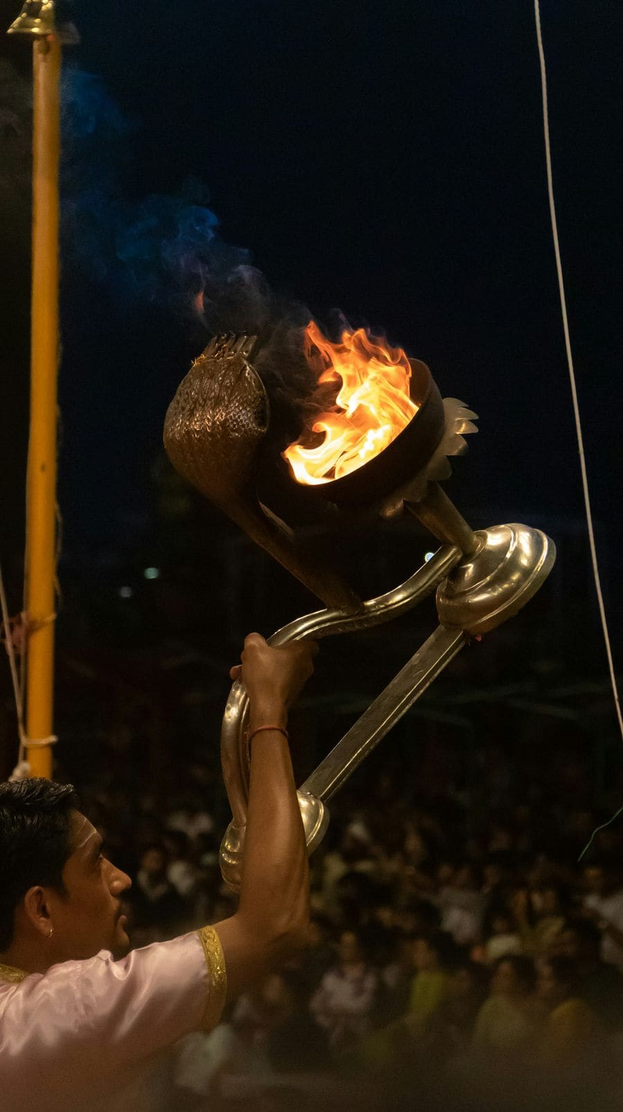 A brass lamp held high with a large open flame at night